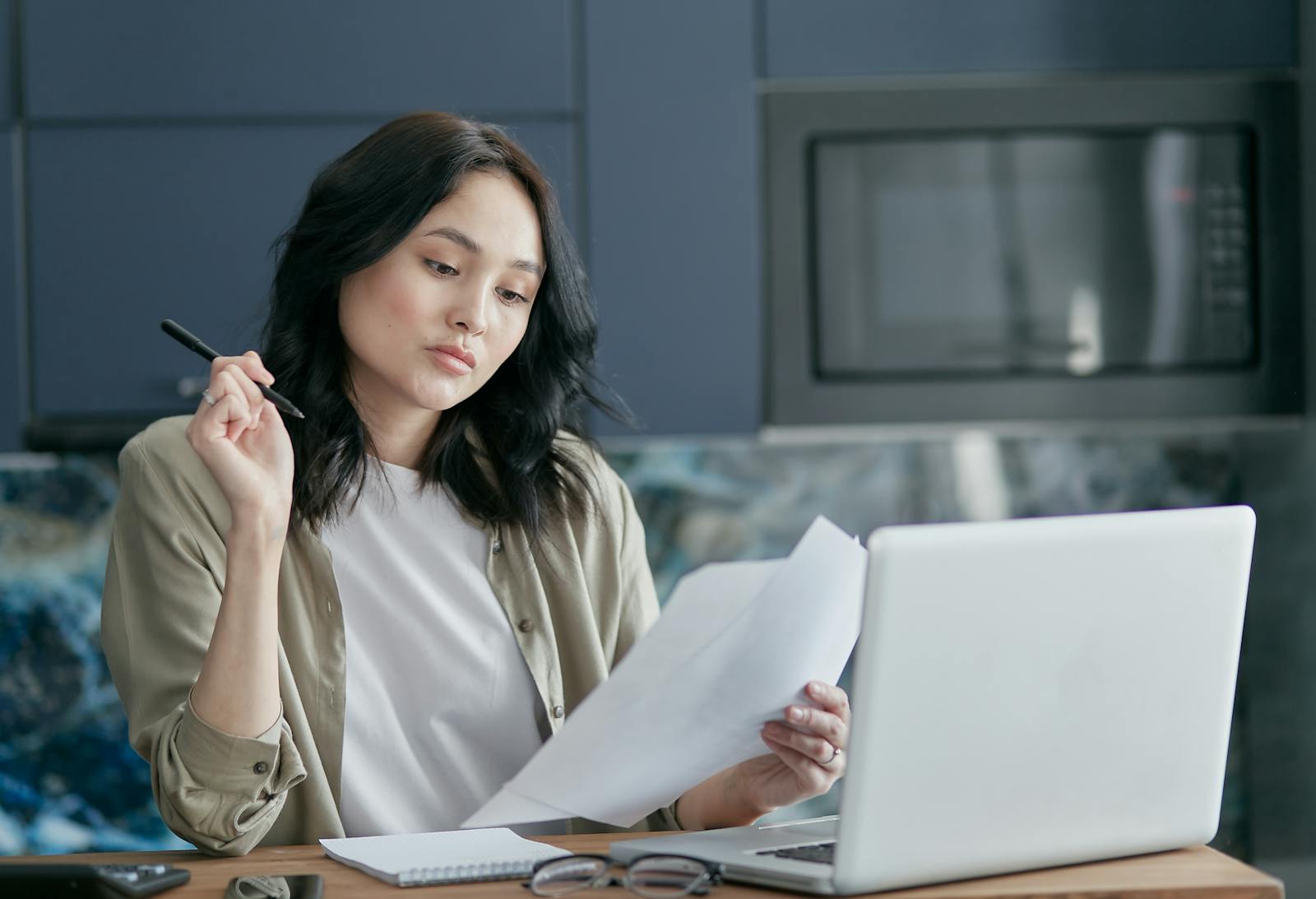 Woman reviewing mortgage documents and working on a laptop